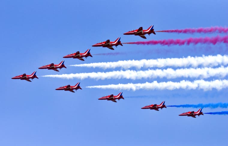 RAF Waddington, UK. July, 6, Royal Air Force Red jets trailing red and white smoke in the sky.