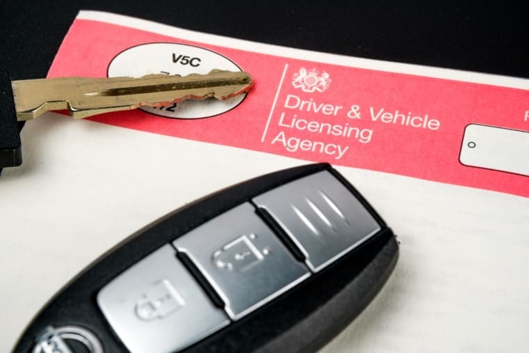 Genuine UK DVLA registration certificate, is needed for a purchased car. Car keys sit atop the paper.
